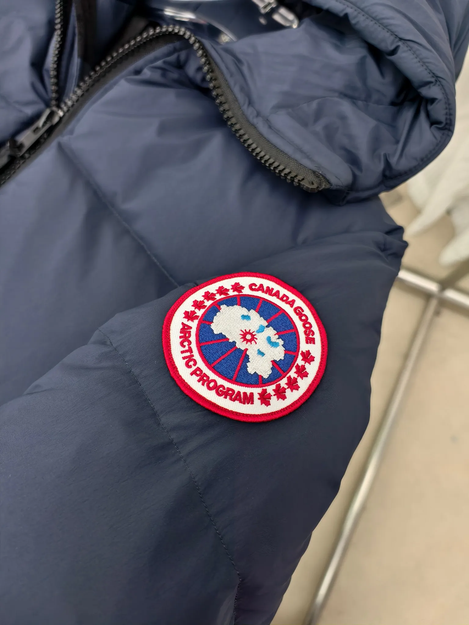 P940 Canada Goose Lawrence Down Jacket The Lawrence Down Jacket provides essential protection for everyday adventures and is made from sustainable Enduraluxe fabric with a durable soft touch. It features a quilted body, an adjustable down hood and a longer hem. Adjustable, down-filled, communicated hood. Two-way center front zipper increases range of motion and ventilation. The chin-protecting suede knit stand-up collar is soft and extra-comfortable. Inset rib-knit cuffs for added comfort and locked in heat. CORDURAD piping at the cuffs hem and reflective double-stripe grip tape at the back. Internal shoulder strap Color: black with red label black with black label azure blue Size: XS-2XL